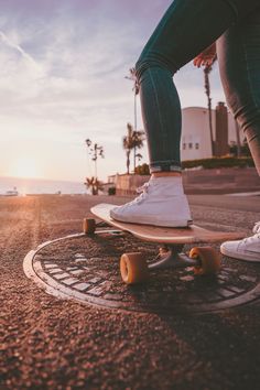 a person riding a skateboard on top of a sidewalk near the ocean and palm trees