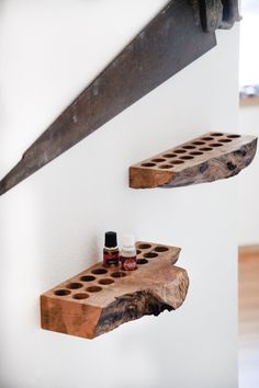 two wooden shelves with bottles on them against a white wall, one shelf is made out of wood