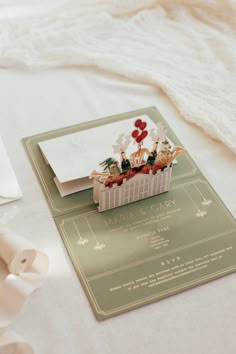 a wedding card with flowers on it sitting on a table next to a white ribbon