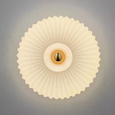 a light that is on in the ceiling with a white wall behind it and an orange circle at the center