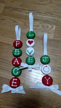 christmas ornaments made out of buttons and ribbons on a wooden floor with the word peace spelled in red, green and white