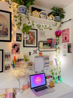 a laptop computer sitting on top of a white desk next to a potted plant