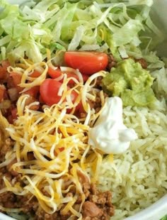 a white bowl filled with rice, meat and veggies next to lettuce