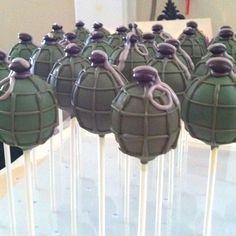 many green cake pops are lined up on a table with candles in the shape of army balls