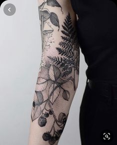 a woman's arm with black and white tattoos on her left arm, flowers and leaves in the background