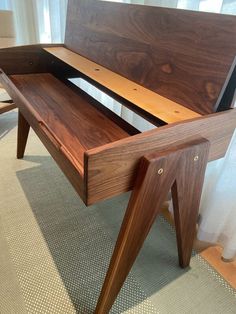 a wooden desk sitting on top of a carpeted floor next to a white curtain