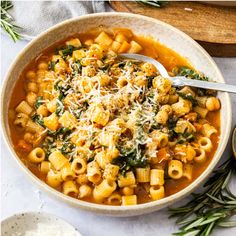 a bowl filled with pasta and spinach covered in parmesan cheese on top