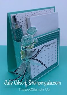 a close up of a desk calendar on a card holder with flowers and ribbons attached to it