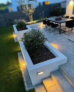 an outdoor dining area is lit up at night, with steps leading to the patio