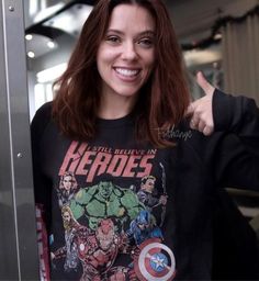 a woman with red hair is smiling and giving the thumbs up while standing in front of an elevator