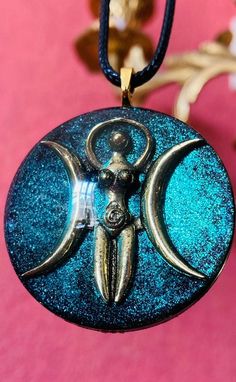 This is a beautiful Goddess resin pendant, with an antique brass symbol of the Triple Moon Goddess. It is approx. 1,75 inch (4cm) and manufactured in high quality resin. The necklace is a black leather chain. The pendant is delivered in a nice pouch. Please note that each pendant is unique and that the end result may not be entirely similar to the pictures. This is due to the fact that the colors blend in their own way, which is never the same twice. The main colors will remain the same though. Hand Painted Spiritual Resin Jewelry, Handmade Celestial Resin Jewelry, Celestial Resin Jewelry As A Gift, Celestial Resin Jewelry For Gifts, Celestial Resin Jewelry As Gift, Celestial Style Resin Jewelry For Gifts, Chalice Well, Goddess Moon, Star Goddess