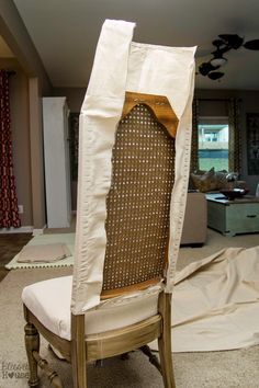 a chair that has been covered with a white cloth and is sitting in the middle of a living room