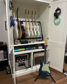 an electric guitar sits in front of a shelf with guitars on it and other musical equipment