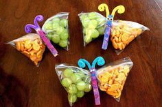 four bags filled with fruit and butterflies on top of a wooden table next to an apple