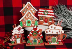 three gingerbread houses with candy canes on a red and black checkered tablecloth