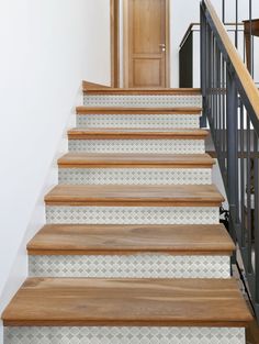 the stairs are made of wood and have white tiles on them, along with black iron railings