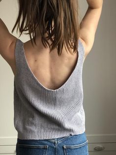 the back of a woman's head with her hands on her hair and wearing jeans