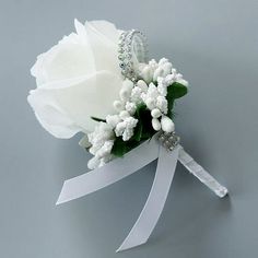 a white rose and baby's breath boutonniere on a gray background