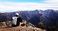 a man sitting on top of a mountain looking at the mountains