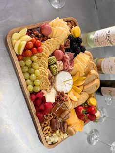 a platter with cheese, crackers, fruit and wine