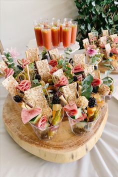 an assortment of appetizers are arranged on a wooden platter with fruit and veggies