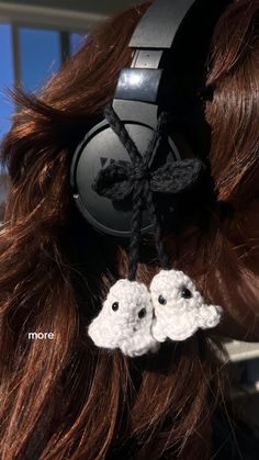 two crocheted sheep headphones are attached to a woman's brown hair