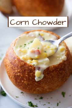 corn chowder in a bread bowl on a white plate with a spoon sticking out of it