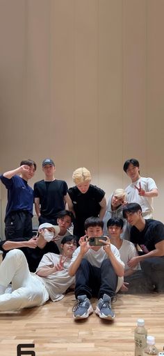 a group of young men sitting next to each other on top of a wooden floor