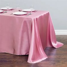 a pink table cloth with white plates on it