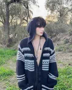 a mannequin is standing in the grass wearing a black and white sweater with hood