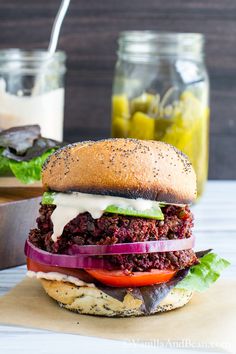 a burger with lettuce, tomato and cheese on it sitting on a cutting board