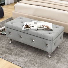 a gray ottoman sitting on top of a rug next to a bed