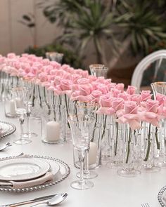 a long table is set with silverware and pink roses in vases on it