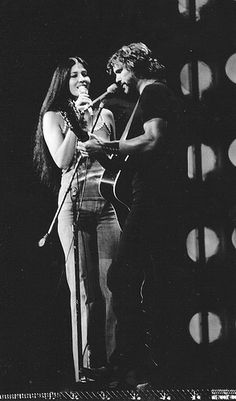 two people on stage singing into microphones