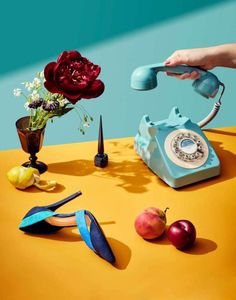 a table topped with an old fashioned telephone next to flowers and other items on top of it