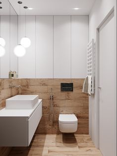 a bathroom with two sinks, a toilet and a shower head mounted to the wall