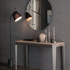 a table with a lamp and a mirror on it next to a wall mounted clock