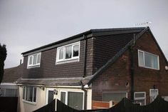 a brown house with white windows and a black fence