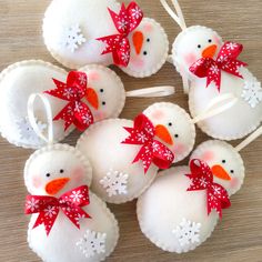 snowman ornaments made out of toilet paper rolls on a wooden table with red bows