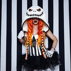 a woman with red hair wearing a white and black striped costume, holding her hands on her hips