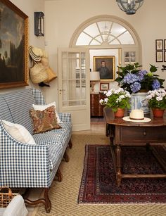 a living room filled with furniture and flowers on top of a wooden table in front of a doorway