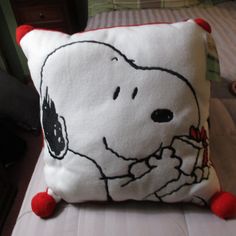 a white pillow with a snoopy dog on it's side and red pom - poms around the edges