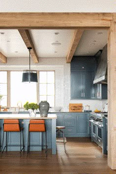 an open kitchen with blue cabinets and orange stools in front of the counter top