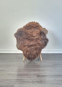 a furry stool sitting on top of a hard wood floor next to a white wall