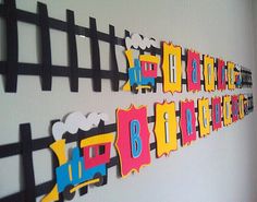 there is a wall decoration made out of paper with train and name cutouts on it