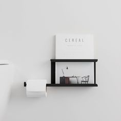 a white toilet sitting next to a black shelf with a book on top of it