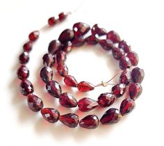 a strand of red glass beads sitting on top of a white table