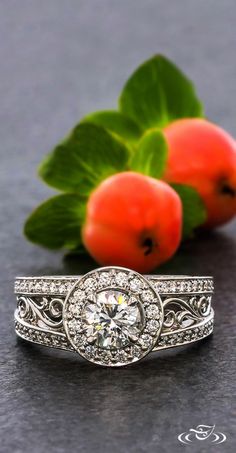 a diamond ring sitting on top of a table next to two peaches and green leaves