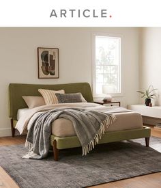 a bed sitting on top of a wooden floor next to a window