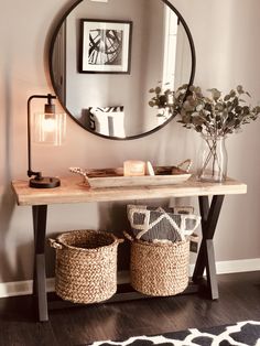 a wooden table topped with baskets under a round mirror